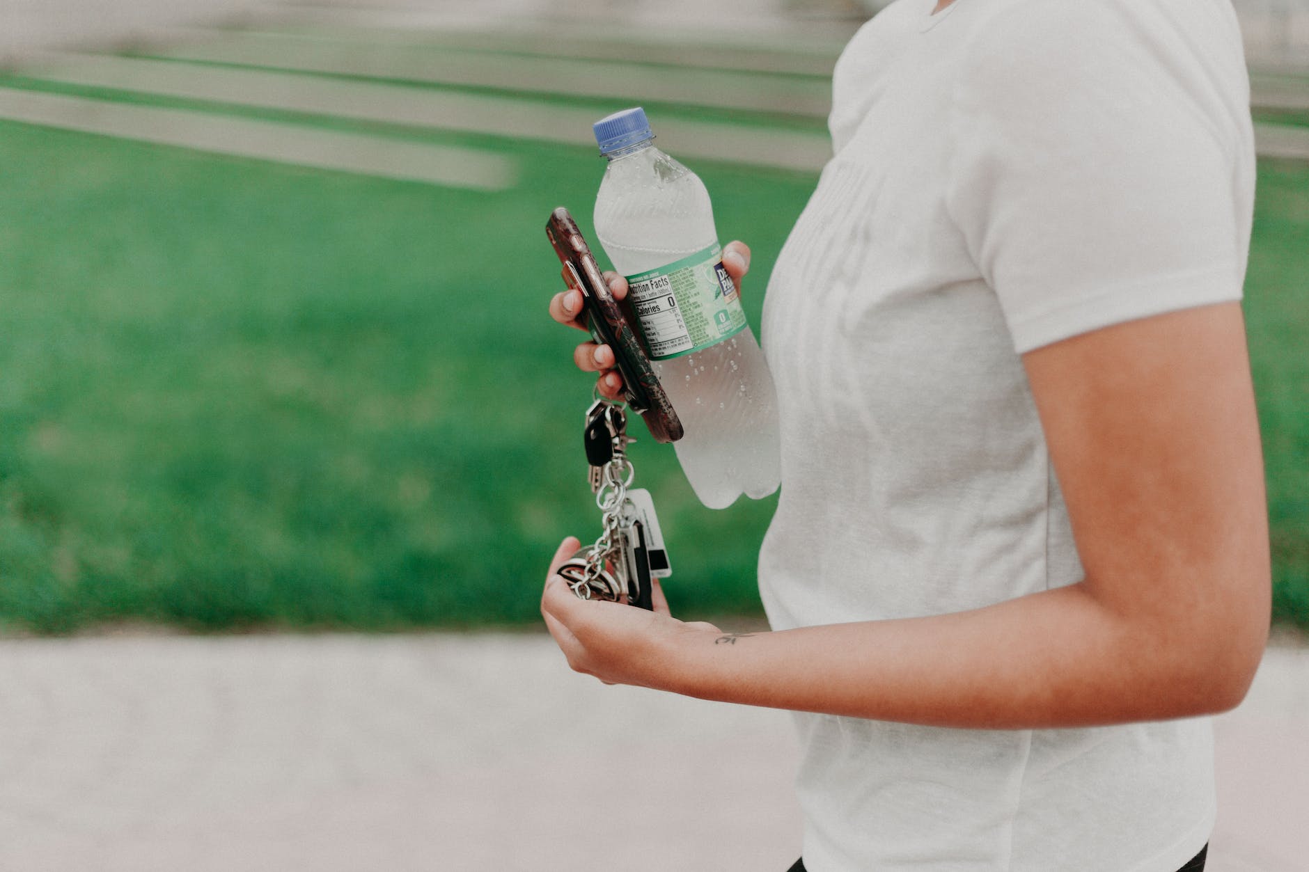 person holding car keys and bottled water